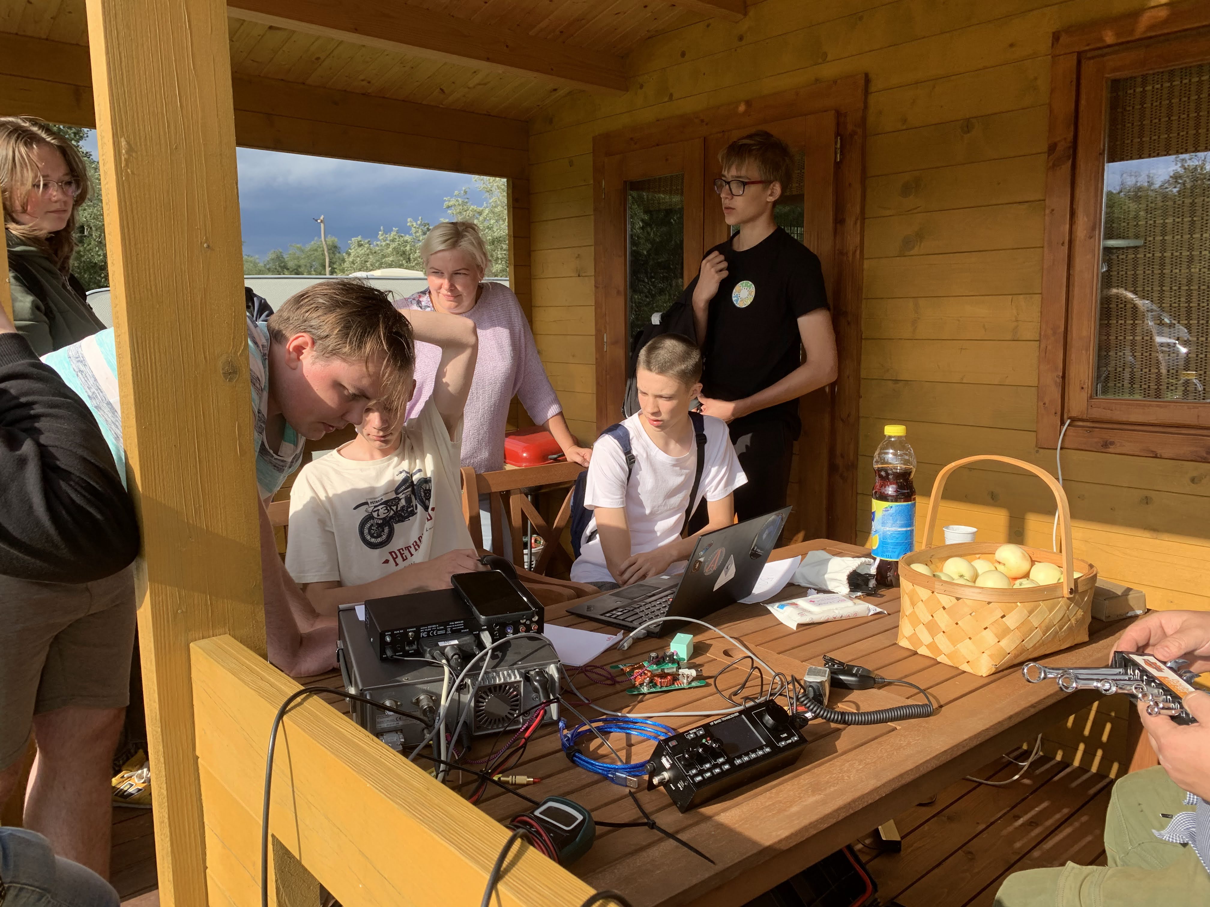 VU radijo klubo sąskrydžio stotis, du mokiniai ruošiasi atlikti ryšius radijo aparatu, klubo narys jiems padeda
